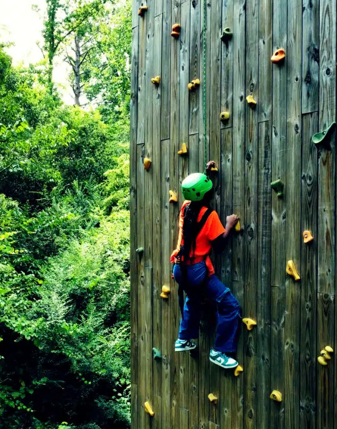 Youth participant climbing an outdoor challenge wall